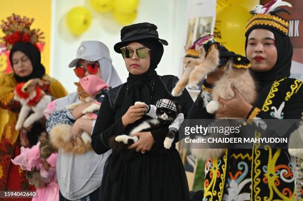 Dressed cats are held by their owners as they participate in the Cat Fashion Week held at a shopping mall in Banda Aceh, northern Indonesia, on...