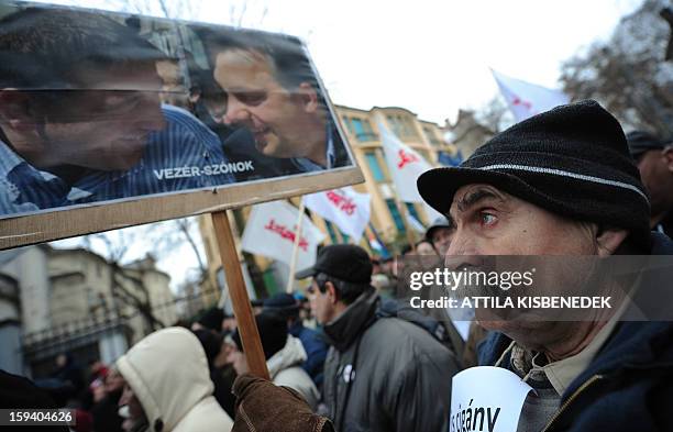 Participant of a rally holds a banner with a photo of Hungarian Prime Minister Viktor Orban and the governor FIDESZ party member Zsolt Bayer during a...