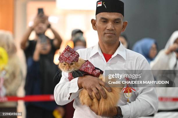 Dressed cat is held by its owner as they participate in the Cat Fashion Week held at a shopping mall in Banda Aceh, northern Indonesia, on August 12,...