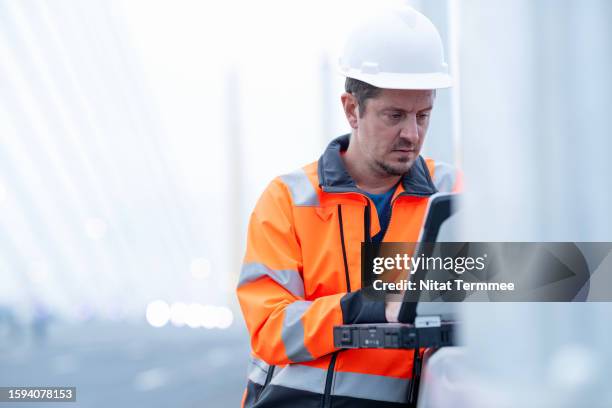 track all aspects of the project with agile project management solution for construction industry. a project manager uses a laptop to track time against a project with access to timesheets and reporting tools through field operation. - civil engineer stock pictures, royalty-free photos & images