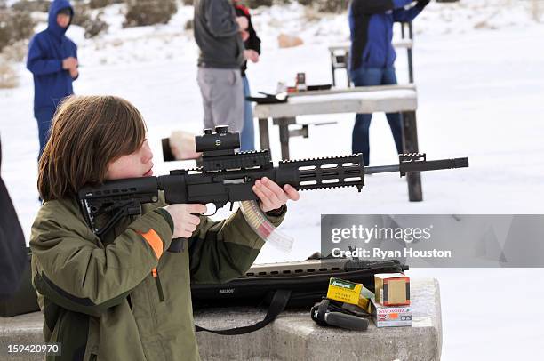 Year old boy shoots glass Christmas ornaments at the shooting range with a .22 assault style rifle. It is a fun family tradition of target practice...