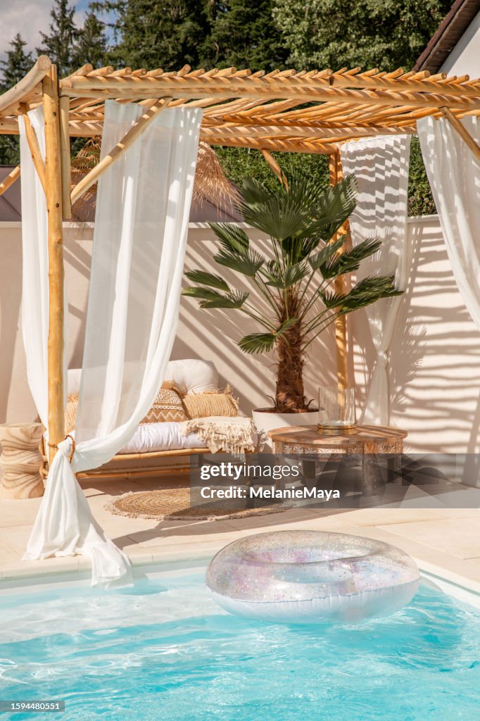 Boho-Bambus-Outdoor-Sofa unter Treibholz-Pergola am Pool in warmem Sonnenlicht