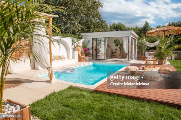 espace piscine privée dans jardin bohème extérieur avec chaises longues sur terrasse en bois et pool house - pergola bois photos et images de collection