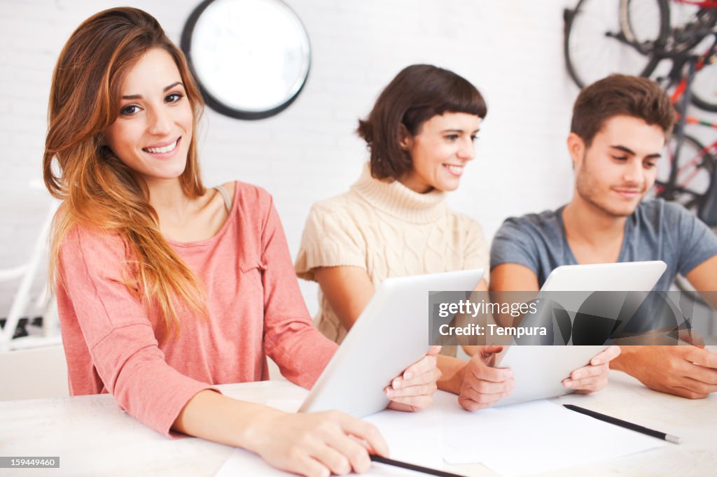 Three people enjoying a digital tablet on work break,