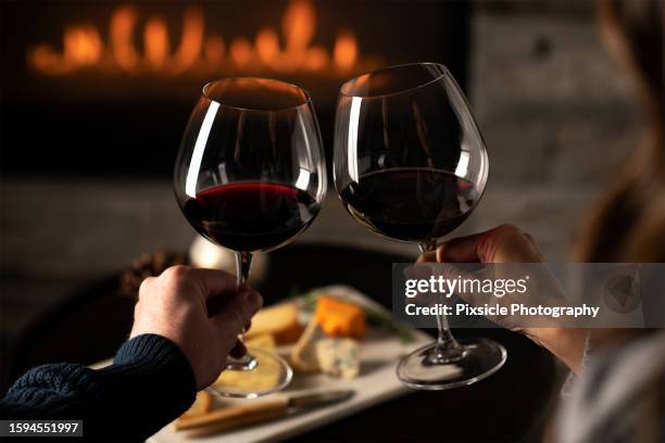 close up of couples hands cheering wine glasses - rode wijn stockfoto's en -beelden
