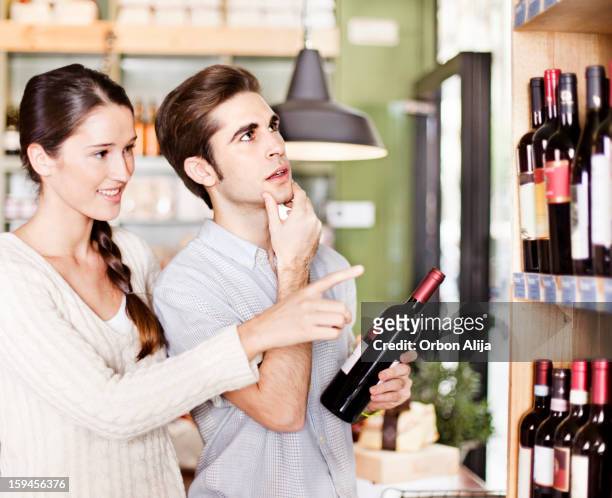 couple picking up wine - choosing wine stock pictures, royalty-free photos & images