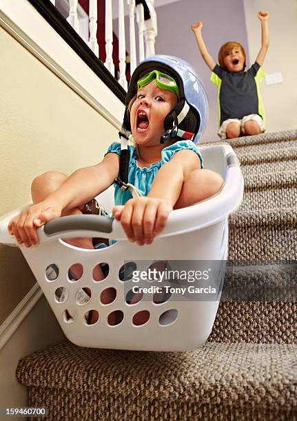 girl going down stairs in laundry basket - misbehaving children stock pictures, royalty-free photos & images