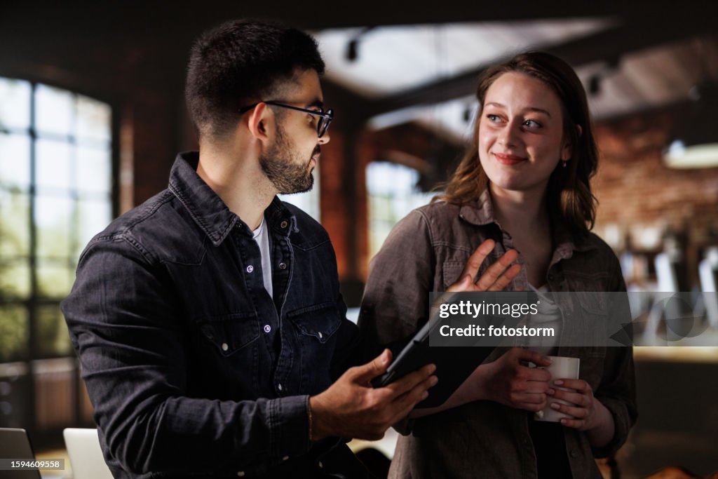 Two colleagues discussing data they are analyzing off of digital tablet