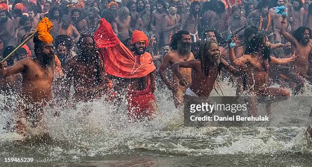 Naga sadhus run in to bathe in the waters of the holy Ganges river during the auspicious bathing day of Makar Sankranti of the Maha Kumbh Mela on...