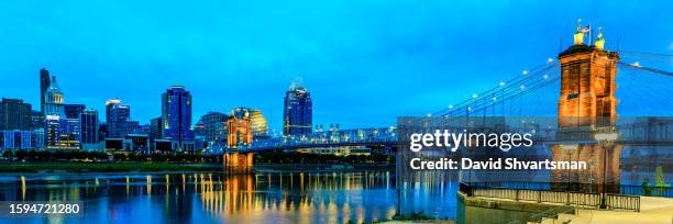 cincinnati downtown skyline with historical roebling suspension bridge lights in the evening - cincinnati, ohio, usa. - ohio stock pictures, royalty-free photos & images