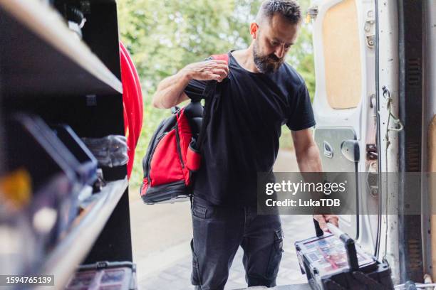 bearded man leaves a bag with his hand tools in the vehicle, after repairing the heating pump - heat pump stock pictures, royalty-free photos & images