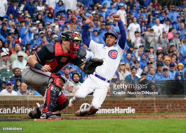 Cody Bellinger of the Chicago Cubs scores against Sean Murphy of the Atlanta Braves during the fifth inning of a game at Wrigley Field on August 05,...