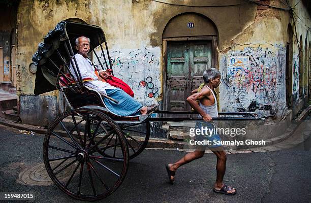 Rickshaw puller is carrying an old man in his hand pulled rickshaw in the lanes of north Kolkata.