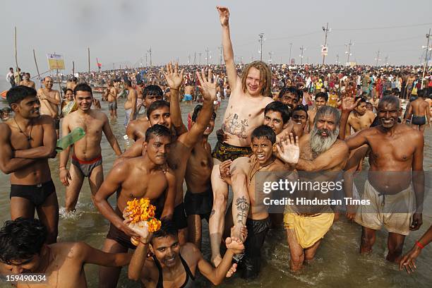 Indians lifting foreigner devotee in air while taking first bath of Kumbh at the bank of Sangam confluence of river Ganga, Yamnuna and mythical...
