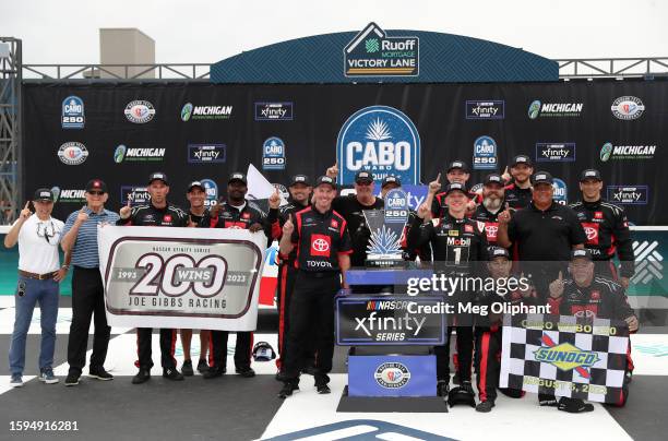 John Hunter Nemechek, driver of the Mobil 1 Toyota, and crew pose with a flag in honor of Joe Gibbs Racing's 200th NASCAR Xfinity Series win, in...