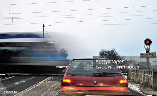 Car waits as a regional train passes at a level crossing in Fletre, northern France, on January 14, 2013. AFP PHOTO / PHILIPPE HUGUEN