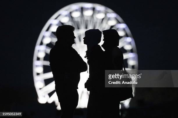 Silhouette of people are seen in front of a ferris wheel during the Bristol International Balloon Fiesta on August 12, 2023 in Bristol, United...