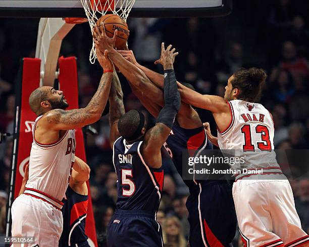 Carlos Boozer and Joakim Noah of the Chicago Bulls battle for a rebound with Josh Smith and Al Horford of the Atlanta Hawks at the United Center on...