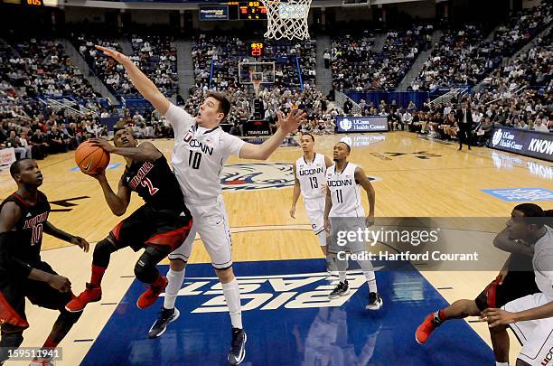 Connecticut Huskies forward Tyler Olander defends the basket as Louisville Cardinals guard Russ Smith attempts a shot during a men's college...