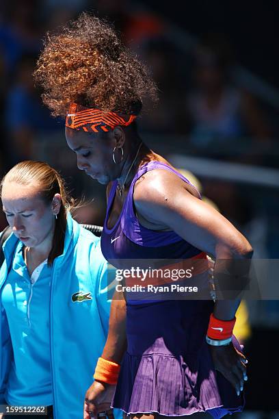 Serena Williams of the United States is assisted from the court after falling onto the court injuring her ankle in her first round match against...