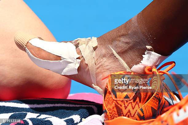 Serena Williams of the United States receives medical attention after falling onto the court injuring her ankle in her first round match against...
