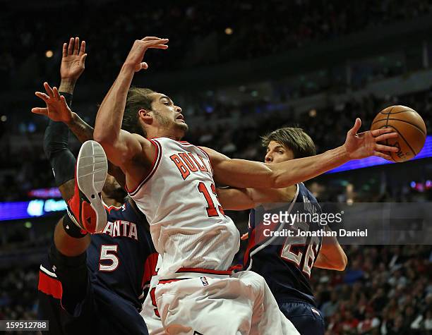 Joakim Noah of the Chicago Bulls tries to control the ball between Josh Smith and Kyle Korver of the Atlanta Hawks at the United Center on January...