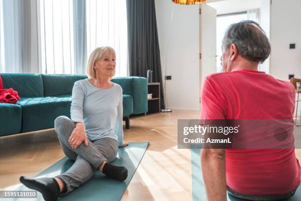 active living: senior couple bonding through exercise - stretching home stock pictures, royalty-free photos & images