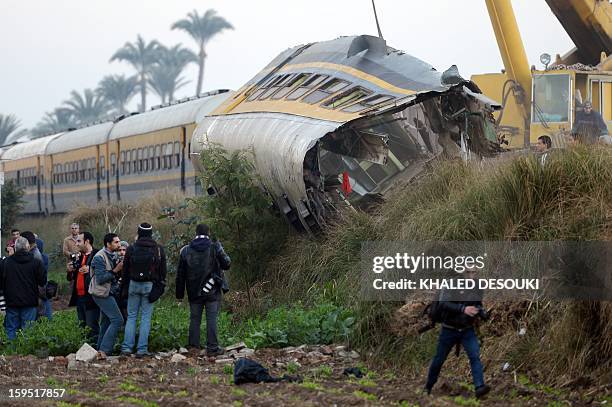 People inspect at the wreckage of a train in the Giza in Badrashin, about 40 km south of Cairo, on January 15 at least 19 people where killed and...