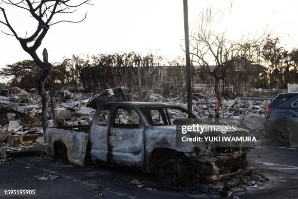 Burnt out car lies in the driveway of charred apartment complex in the aftermath of a wildfire in Lahaina, western Maui, Hawaii on August 12, 2023....