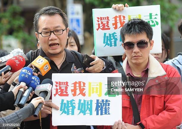Chen Ching-hsueh and his partner Kao Chih-wei display placards reading " return my marriage rights " outside the Taipei High Administrative Court on...