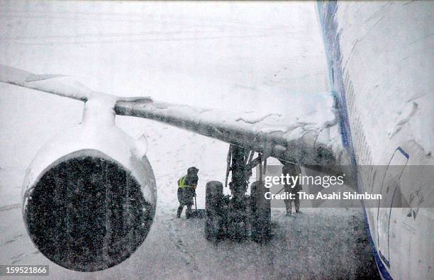 Airport staffs wait under the airplane at Sendai Airport on January 14, 2013 in Natori, Miyagi, Japan. The airport is once closed due to the heavy...