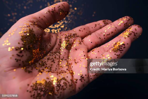 bright golden sequins on the hand. - cleaning after party - fotografias e filmes do acervo