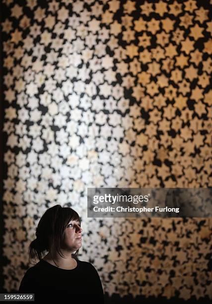 Ceramic artist Chava Rosenzweig poses next to her installation of ceramic stars representing how the Holocaust shaped people's lives, on January 15,...
