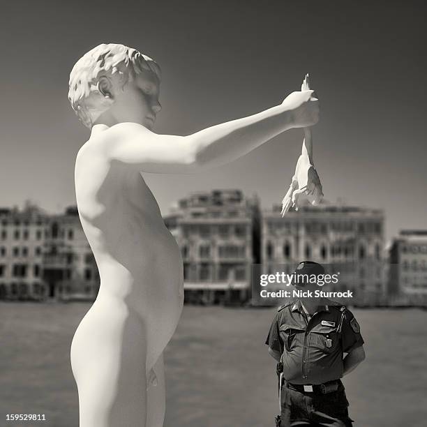 Venetian policeman patrols beneath a giant statue of a boy holding a frog, on the banks of the Gran Canal