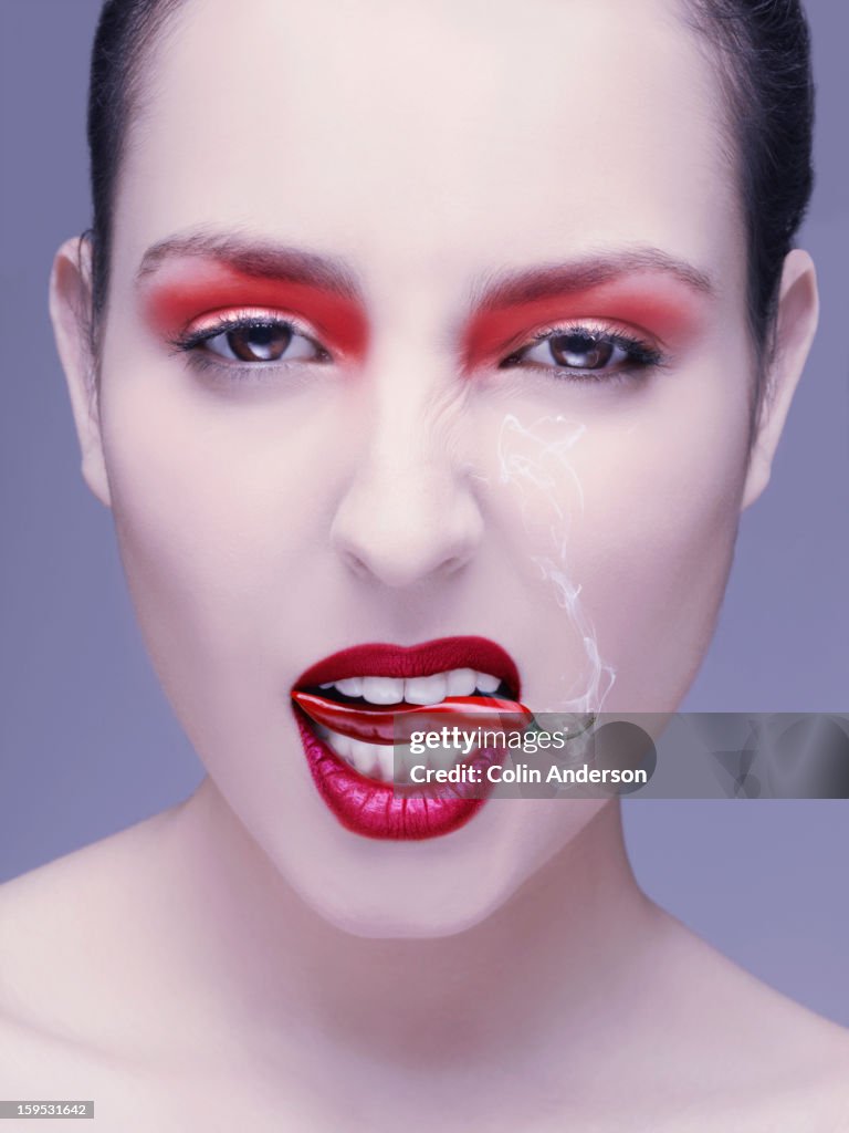 A woman with a smoking chilli in her mouth