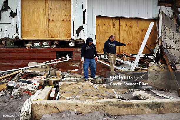 Contractors Rob Curtis and Rene Huerta look at a damaged home that they had been remodeling Discarded items from before Hurricane Sandy along the...