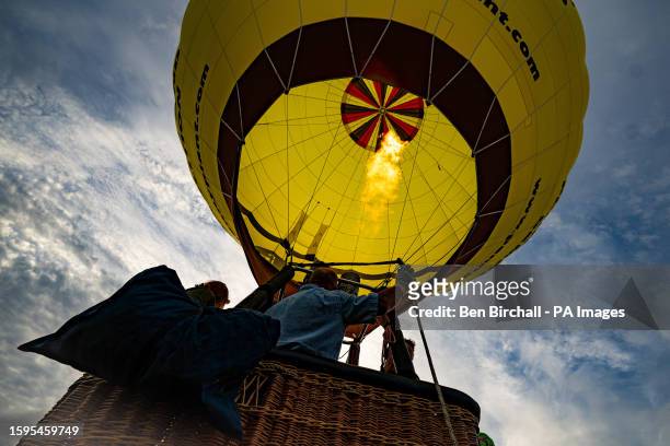 Hot air balloon pilots test the burners prior to flight as balloons take off on the last day of the Bristol International Balloon Fiesta, at Ashton...