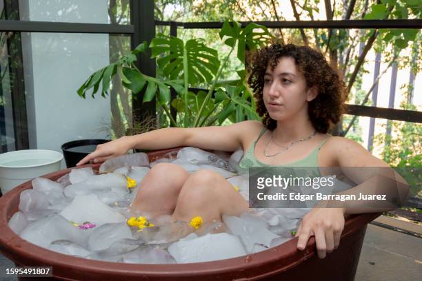 young mexican woman taking an ice bath outdoors while taking a deep breath - bad breath stockfoto's en -beelden