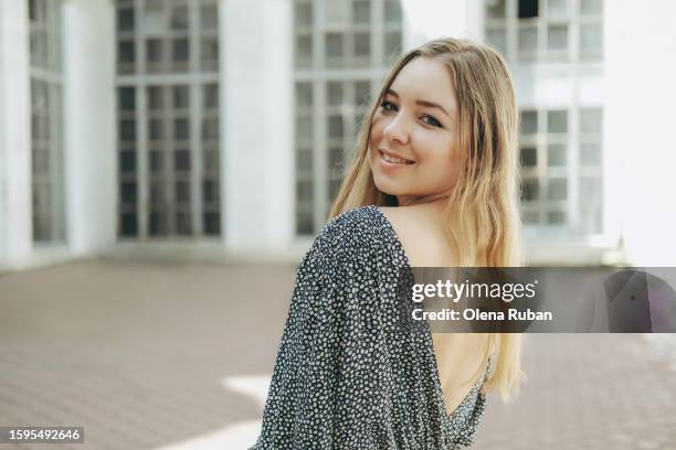 young woman in flower dress against a building with high windows. - human face people grid stock pictures, royalty-free photos & images