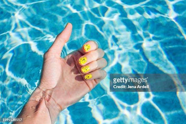 woman's wrist in swimming pool, woman's hand, yellow nail polish summer fingernails - aqua nail polish stock pictures, royalty-free photos & images