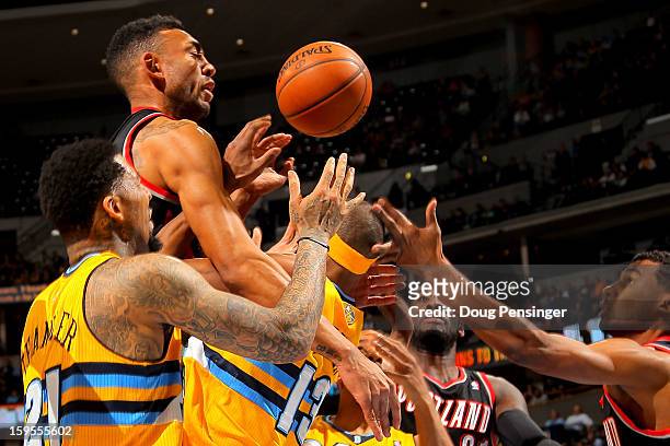 Jared Jeffries of the Portland Trail Blazers crashes over Wilson Chandler of the Denver Nuggets and Corey Brewer of the Denver Nuggets as they vie...