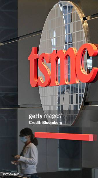 The Taiwan Semiconductor Manufacturing Co. Logo is displayed as an employee is reflected entering the company's headquarters in Hsinchu, Taiwan, on...