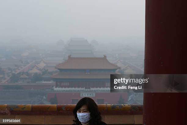 Tourist wearing the mask looks on as pollution covers the Forbidden City on January 16, 2013 in Beijing, China. Heavy smog shrouded Beijing with...