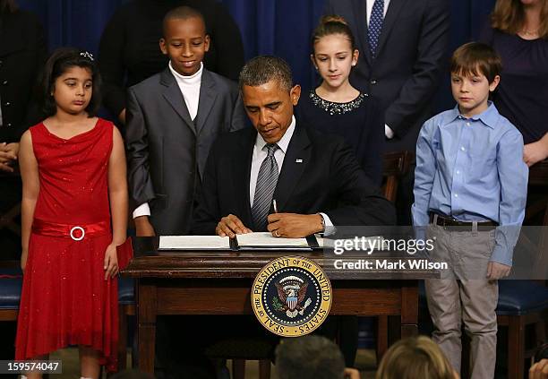 President Barack Obama is flanked by young children as he signs an executive order designed to tackle gun control, on January 16, 2012 in Washington,...