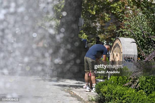 Man wash his hands to cool off as the fountain pours in the park during the hot weather in Ankara, Turkiye on August 13, 2023.