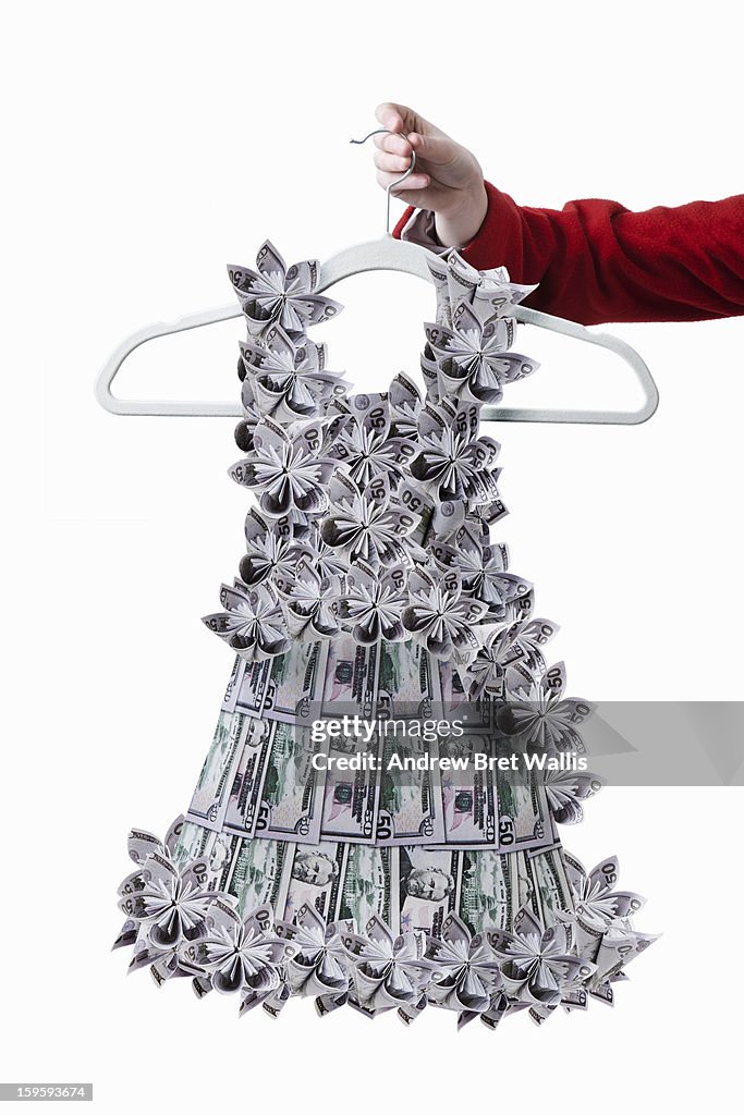 Woman holds origami dollar note dress on a hanger