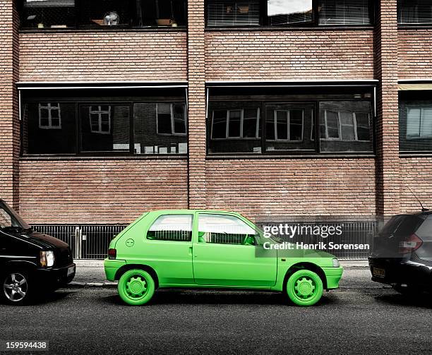 green car, sustainable energy. (by sidewalk) - car parked stock-fotos und bilder