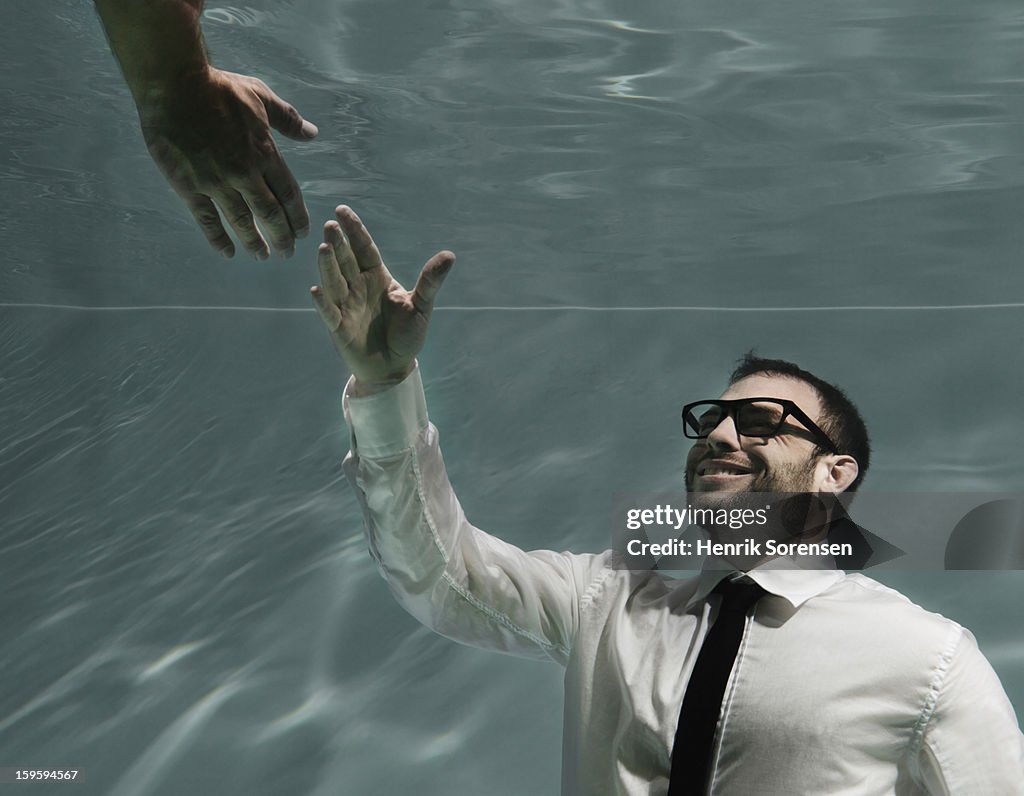 Underwater businessman. (Reaching out)