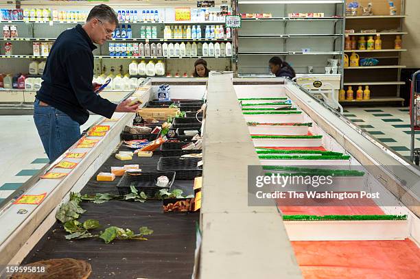 Jeff Neiman of North Potomac nabs one of the last packages of cheese at a nearly empty food bin at Magruder's Tuesday, January 15, 2013 in...