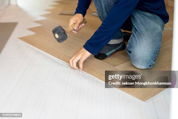 the man uses hammer or mallet to install the parquet floor - parquet flottant photos et images de collection